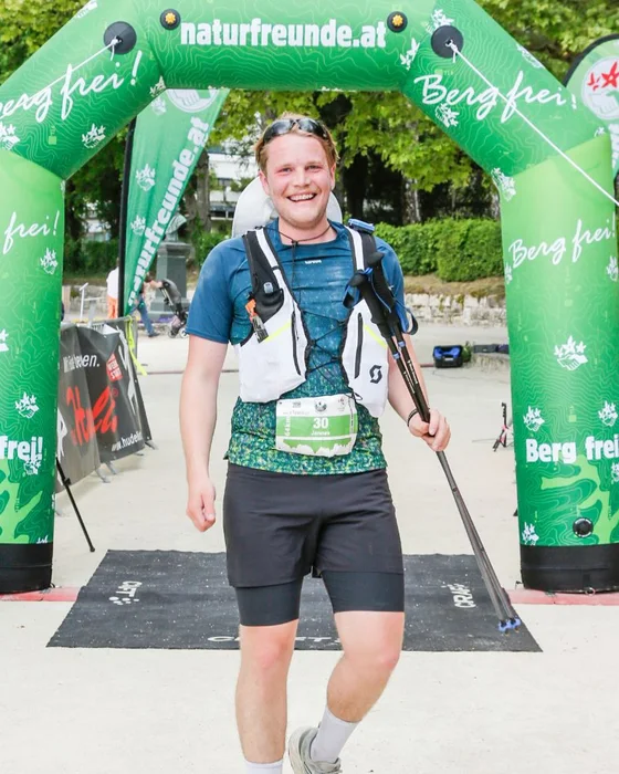 Jannes lachend over de finish van een ultramarathon in Oostenrijk